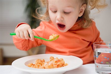 Small girl eating pasta with tomato sauce and Parmesan Stock Photo - Premium Royalty-Free, Code: 659-01851213