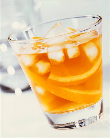 simsearch:659-03527195,k - Un verre de jus d'orange avec des cubes de glace et de tranches d'orange Photographie de stock - Premium Libres de Droits, Code: 659-01851750