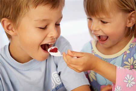 Girl putting a spoonful of yoghurt into a boy's mouth Stock Photo - Premium Royalty-Free, Code: 659-01852196