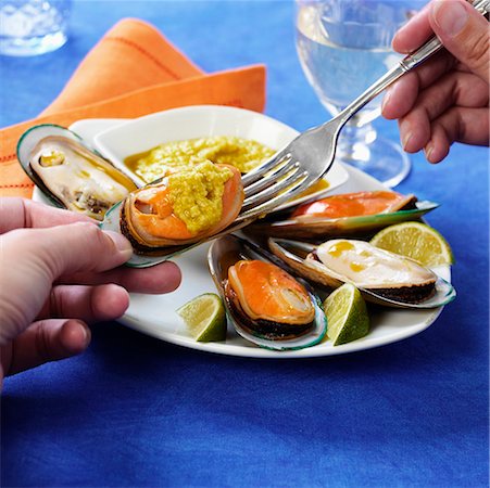 Taking mussels and dip out of shell with a fork Stock Photo - Premium Royalty-Free, Code: 659-01852191