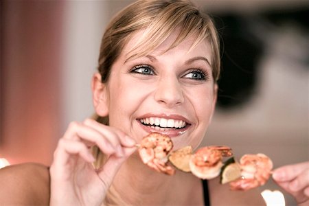 Young woman with shrimp kebab in her hand Stock Photo - Premium Royalty-Free, Code: 659-01852928