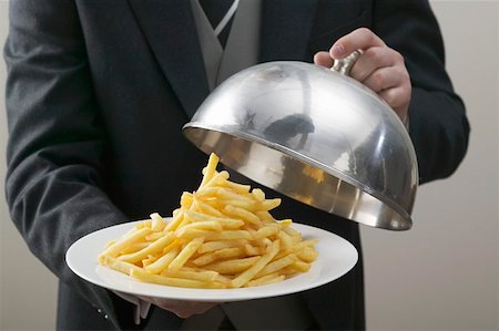 Butler lifting serving dome from plate of chips Stock Photo - Premium Royalty-Free, Code: 659-01864113