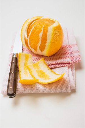 Peeled orange on tea towel with knife Stock Photo - Premium Royalty-Free, Code: 659-01864221