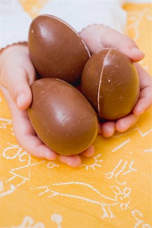 Child's hands holding three chocolate eggs Fotografie stock - Premium Royalty-Free, Codice: 659-01864315