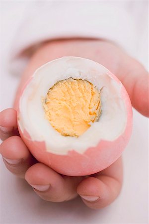 Child's hands holding coloured boiled egg with top cut off Foto de stock - Sin royalties Premium, Código: 659-01864325