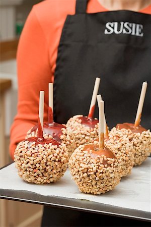 Woman holding a tray of toffee apples with chopped nuts Stock Photo - Premium Royalty-Free, Code: 659-01864414