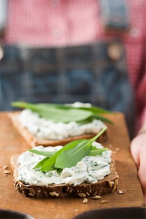 Person holding wholemeal bread with quark & ramsons on board Stock Photo - Premium Royalty-Free, Code: 659-01864603