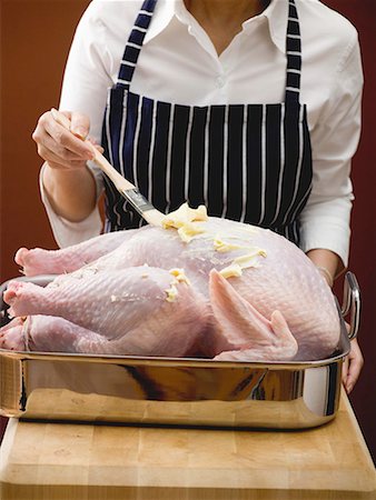 Woman brushing stuffed turkey with butter Stock Photo - Premium Royalty-Free, Code: 659-01864909