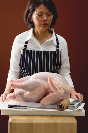 Woman with fresh turkey on chopping board Stock Photo - Premium Royalty-Free, Code: 659-01864915