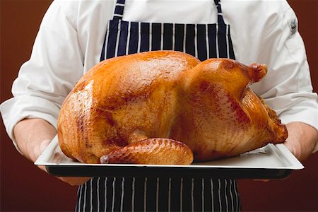 Chef holding stuffed roast turkey on baking tray Stock Photo - Premium Royalty-Free, Code: 659-01864922