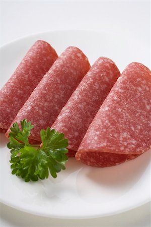 simsearch:659-01865113,k - 4 Tranches de salami avec du persil sur plaque Photographie de stock - Premium Libres de Droits, Code: 659-01865061