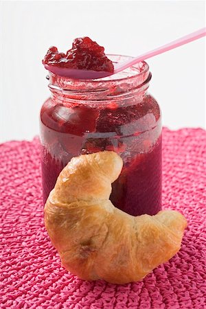 raspberry preserve - Jar of raspberry jam with spoon, croissant in foreground Stock Photo - Premium Royalty-Free, Code: 659-01865153