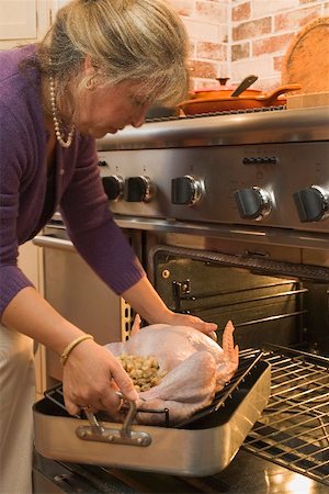 roasting pan - Woman putting stuffed turkey into the oven Stock Photo - Premium Royalty-Free, Code: 659-01865178