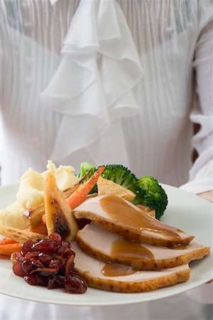 Woman serving turkey breast & accompaniments, Thanksgiving (USA) Stock Photo - Premium Royalty-Free, Code: 659-01865220