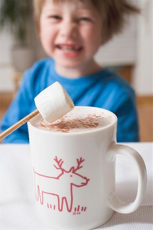 Cup of cocoa with marshmallow, small boy in background Fotografie stock - Premium Royalty-Free, Codice: 659-01865359