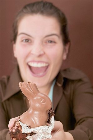 simsearch:659-01865781,k - Laughing woman holding chocolate Easter Bunny with a bite taken Foto de stock - Sin royalties Premium, Código: 659-01865518