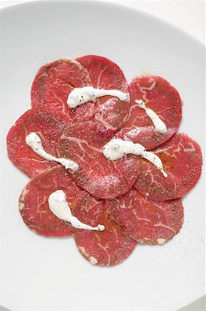 Beef carpaccio with yoghurt sauce (overhead view) Fotografie stock - Premium Royalty-Free, Codice: 659-01865566