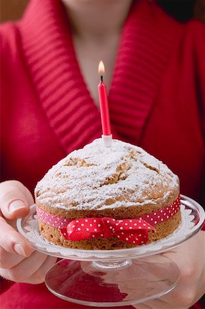 Woman serving birthday cake with bow and candle Stock Photo - Premium Royalty-Free, Code: 659-01865709