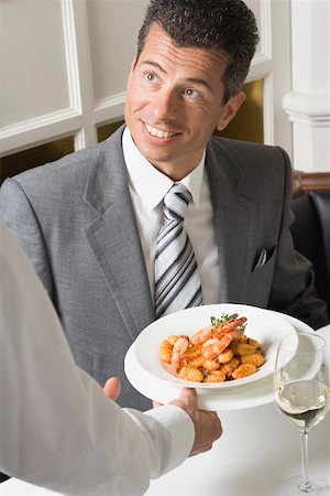 Waiter serving gnocchi with prawns to man Stock Photo - Premium Royalty-Free, Code: 659-01865864