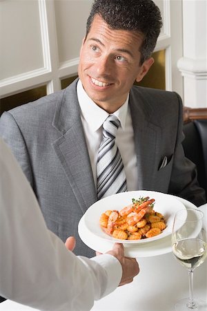 serving seafood - Waiter serving gnocchi with prawns to man Stock Photo - Premium Royalty-Free, Code: 659-01865864