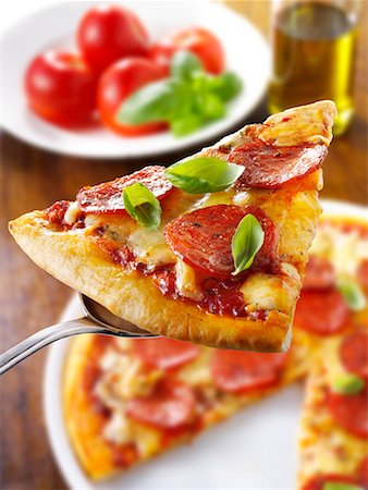 pepperonisalami - Stück Salami Pizza mit Basilikum auf server Stockbilder - Premium RF Lizenzfrei, Bildnummer: 659-01866071