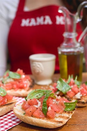 simsearch:659-01845699,k - Bruschetta with tomato salsa, woman in background Foto de stock - Royalty Free Premium, Número: 659-01866450