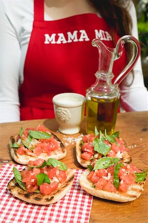 simsearch:659-03525182,k - Bruschetta with tomato salsa, woman in background Stock Photo - Premium Royalty-Free, Code: 659-01866452