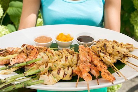 poultry skewer - Woman holding large platter of satay and dips Stock Photo - Premium Royalty-Free, Code: 659-01867117