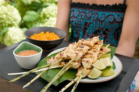 satay - Woman holding tray of satay and dips Stock Photo - Premium Royalty-Free, Code: 659-01867120