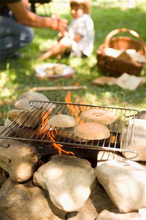 fire bbq - Melon on grill rack over camp- fire, child in background Stock Photo - Premium Royalty-Free, Code: 659-01867146