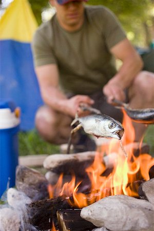 Man grilling fish over camp-fire Stock Photo - Premium Royalty-Free, Code: 659-01867177