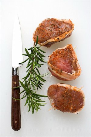 Pork fillet barded with bacon, rosemary, knife Foto de stock - Sin royalties Premium, Código: 659-01867486