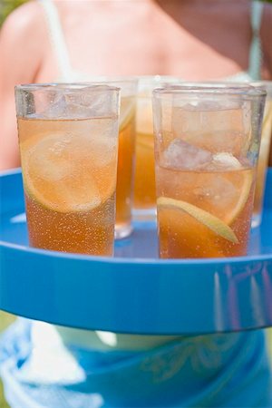 Several glasses of iced tea on tray, woman in background Stock Photo - Premium Royalty-Free, Code: 659-01867665