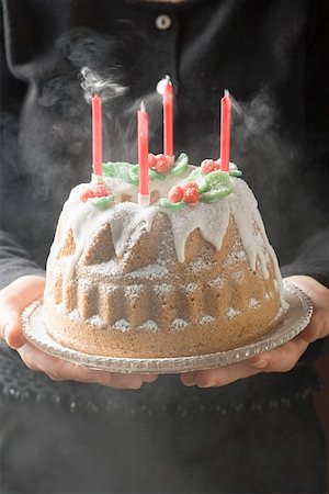 Woman serving walnut gugelhupf with four blown-out candles Stock Photo - Premium Royalty-Free, Code: 659-01860125