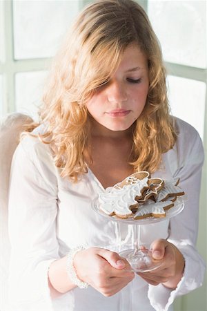 simsearch:659-03525275,k - Blond girl holding glass bowl of assorted gingerbread biscuits Fotografie stock - Premium Royalty-Free, Codice: 659-01860142