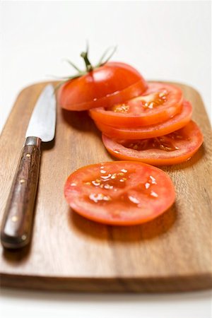 Tomato slices and knife on chopping board Stock Photo - Premium Royalty-Free, Code: 659-01860483