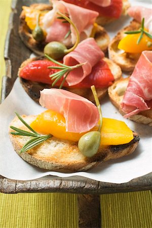 Crostini with raw ham, peppers and giant capers Fotografie stock - Premium Royalty-Free, Codice: 659-01860860