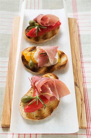 Several crostini with raw ham, peppers and giant capers Fotografie stock - Premium Royalty-Free, Codice: 659-01860924