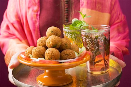 Woman holding tray of falafel (chick-pea balls) and tea Stock Photo - Premium Royalty-Free, Code: 659-01861436