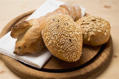 sesame bread - Baguette and wholemeal rolls on breadboard Stock Photo - Premium Royalty-Free, Code: 659-01861606