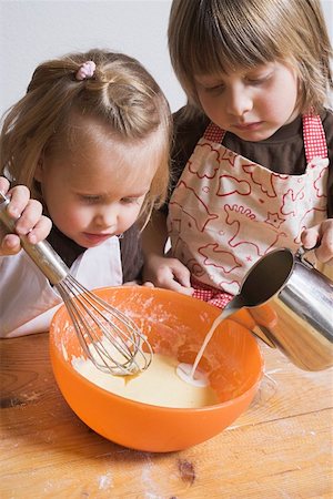 Two children baking (pouring milk into bowl) Stock Photo - Premium Royalty-Free, Code: 659-01861758