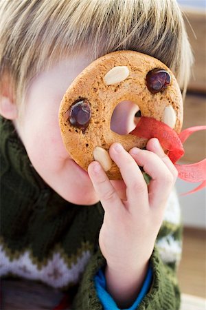 simsearch:659-03529414,k - Small boy holding gingerbread tree ornament in front of his face Fotografie stock - Premium Royalty-Free, Codice: 659-01861814