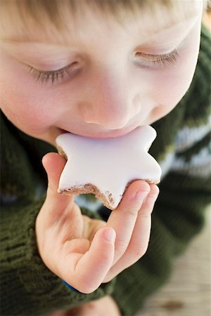 Small boy biting into a cinnamon star Stock Photo - Premium Royalty-Free, Code: 659-01861827