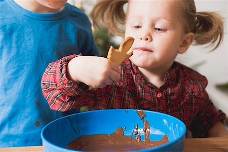 Girl dipping Christmas biscuit in chocolate icing Stock Photo - Premium Royalty-Free, Code: 659-01861861