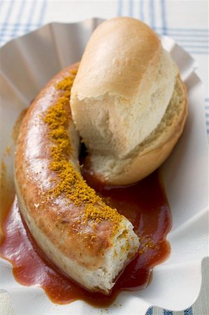 Sausage with curry powder, ketchup & bread roll (partly eaten) Stock Photo - Premium Royalty-Free, Code: 659-01862117