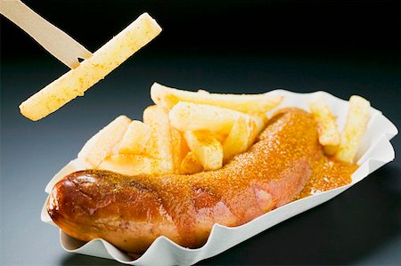 Sausage with ketchup & curry powder & chips, one on wooden fork Stock Photo - Premium Royalty-Free, Code: 659-01862174