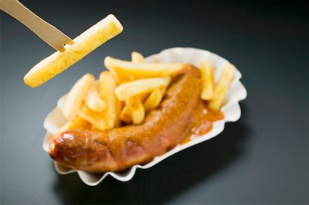 Ssausage with ketchup & curry powder & chips, one on wooden fork Stock Photo - Premium Royalty-Free, Code: 659-01862175