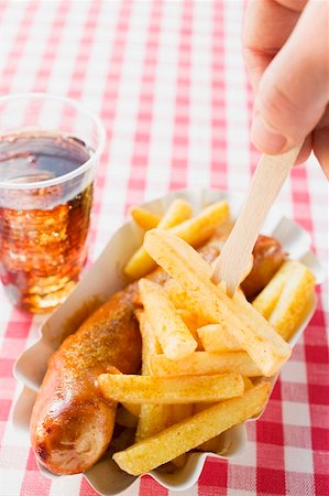 Currywurst with chips, one on wooden fork, and cola Stock Photo - Premium Royalty-Free, Code: 659-01862188