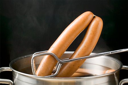 Lifting frankfurters out of hot water with tongs Stock Photo - Premium Royalty-Free, Code: 659-01862325