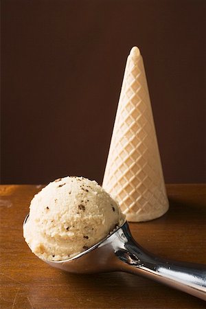 Scoop of ice cream in ice cream scoop, ice cream cone behind Stock Photo - Premium Royalty-Free, Code: 659-01862476